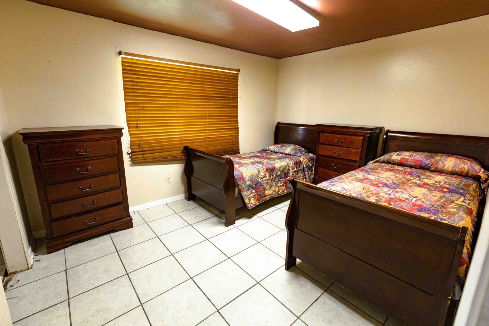 A tidy bedroom with two twin beds and wooden furniture.