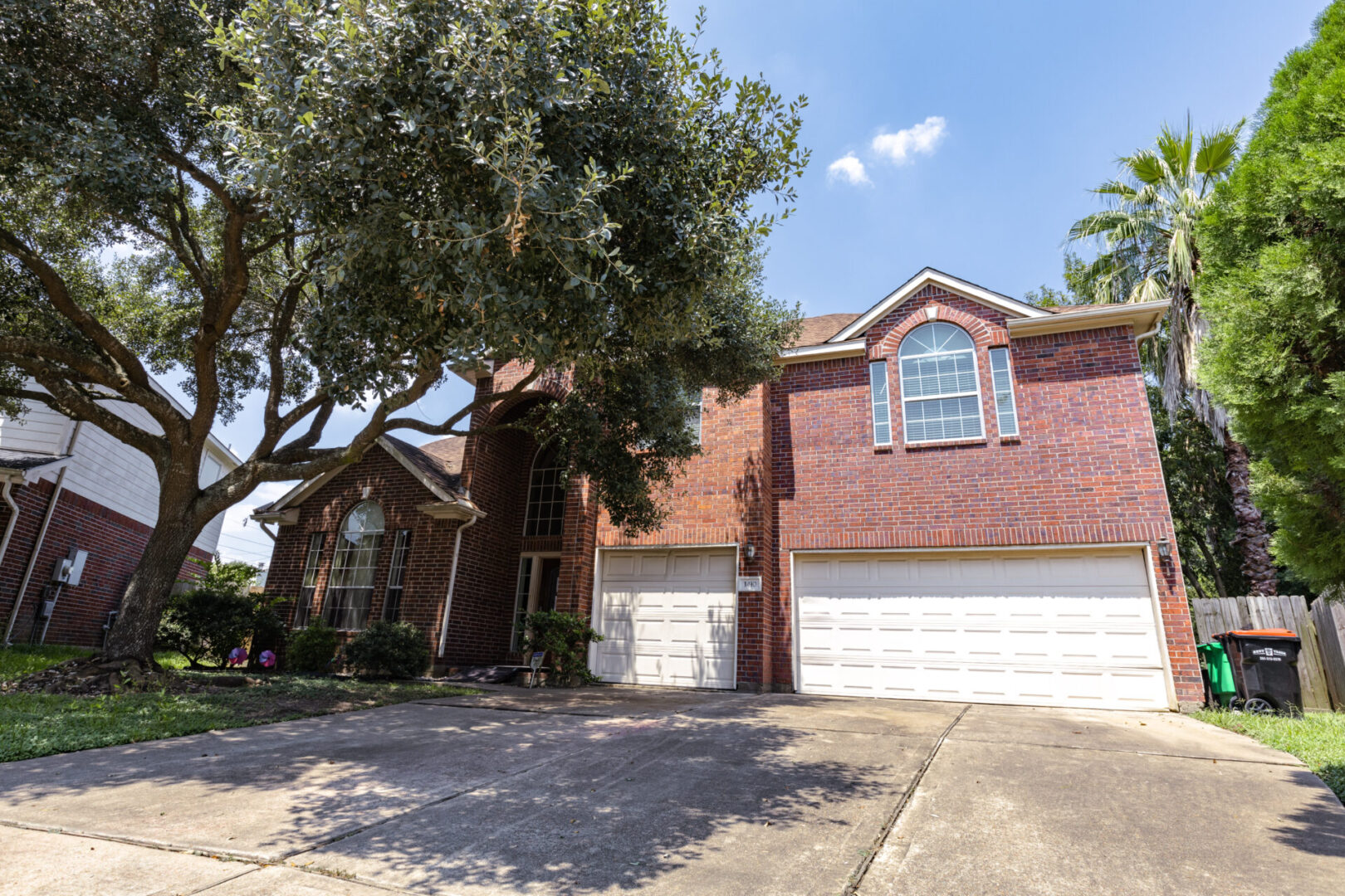 Two-story brick house with a large tree and three-car garage.