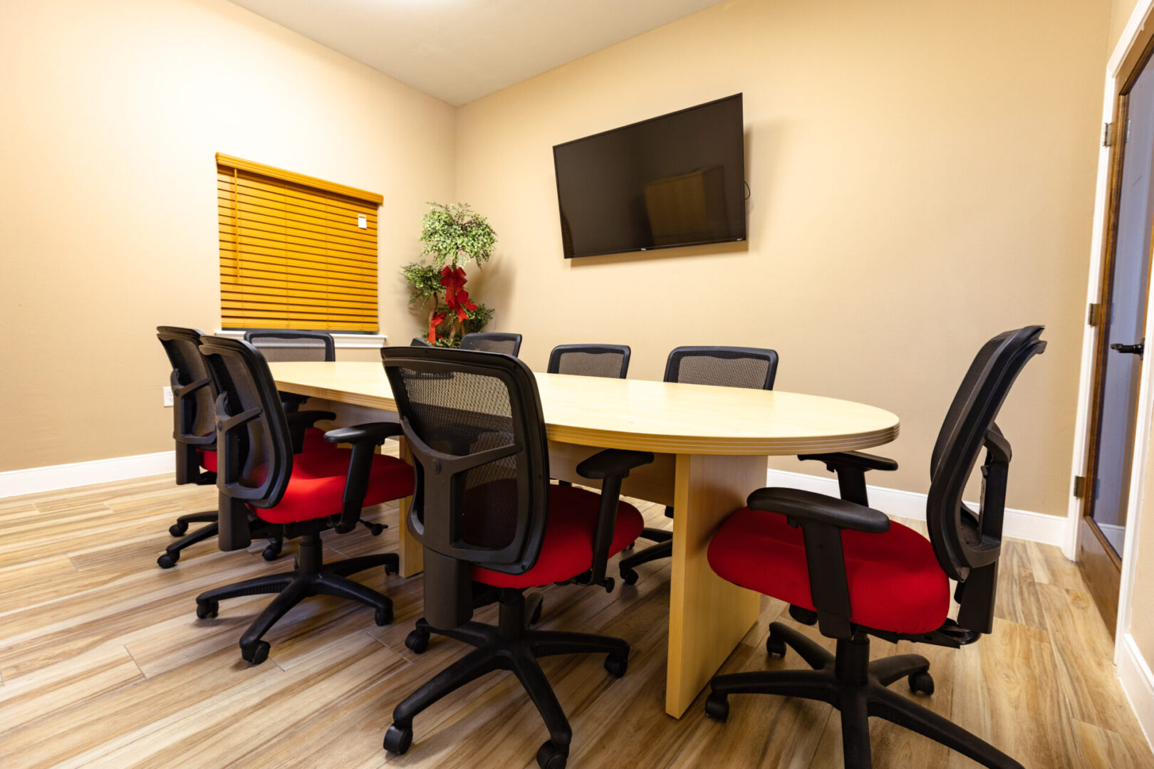 Modern conference room with oval table and ergonomic chairs.