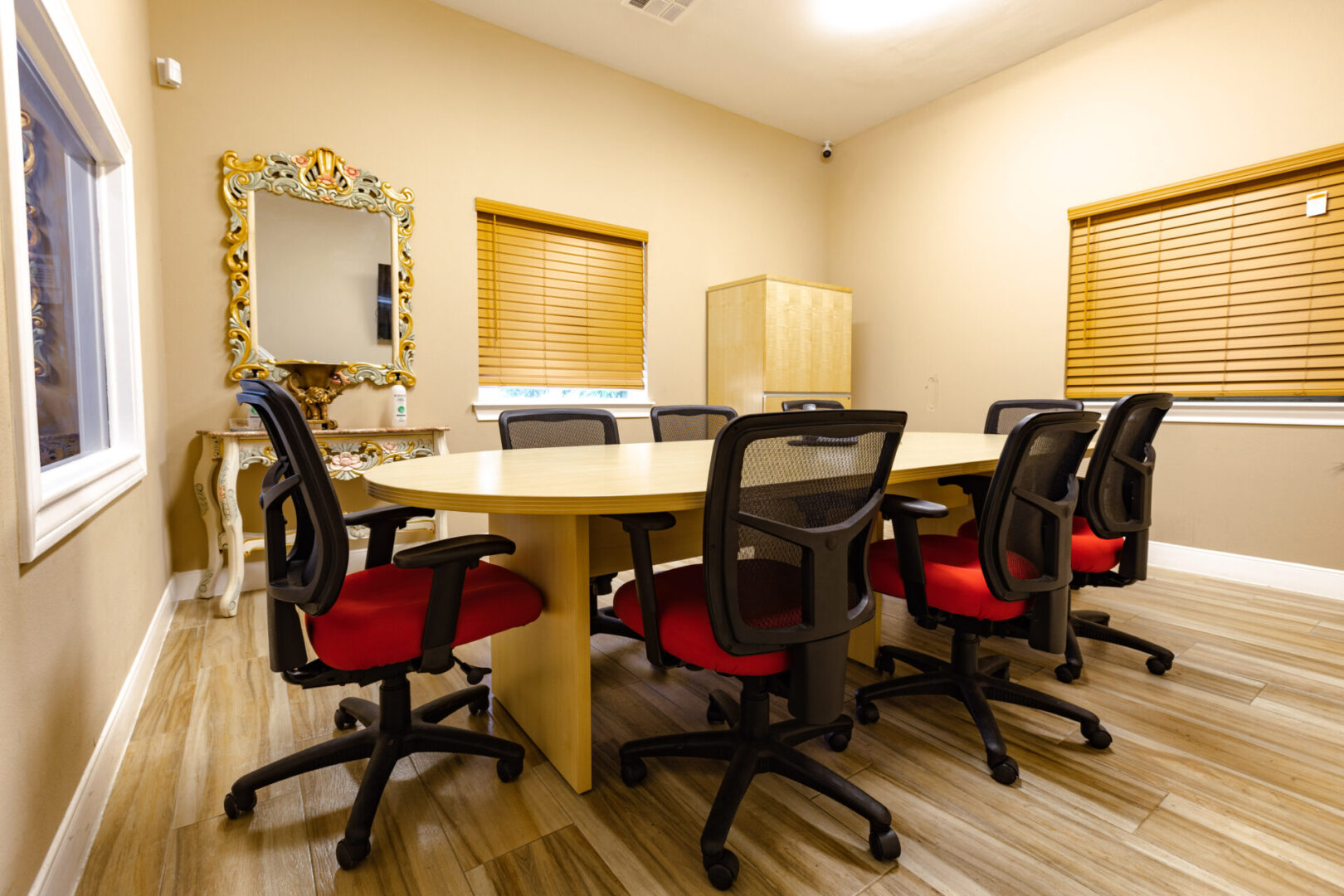 Modern conference room with a wooden table and black mesh chairs.